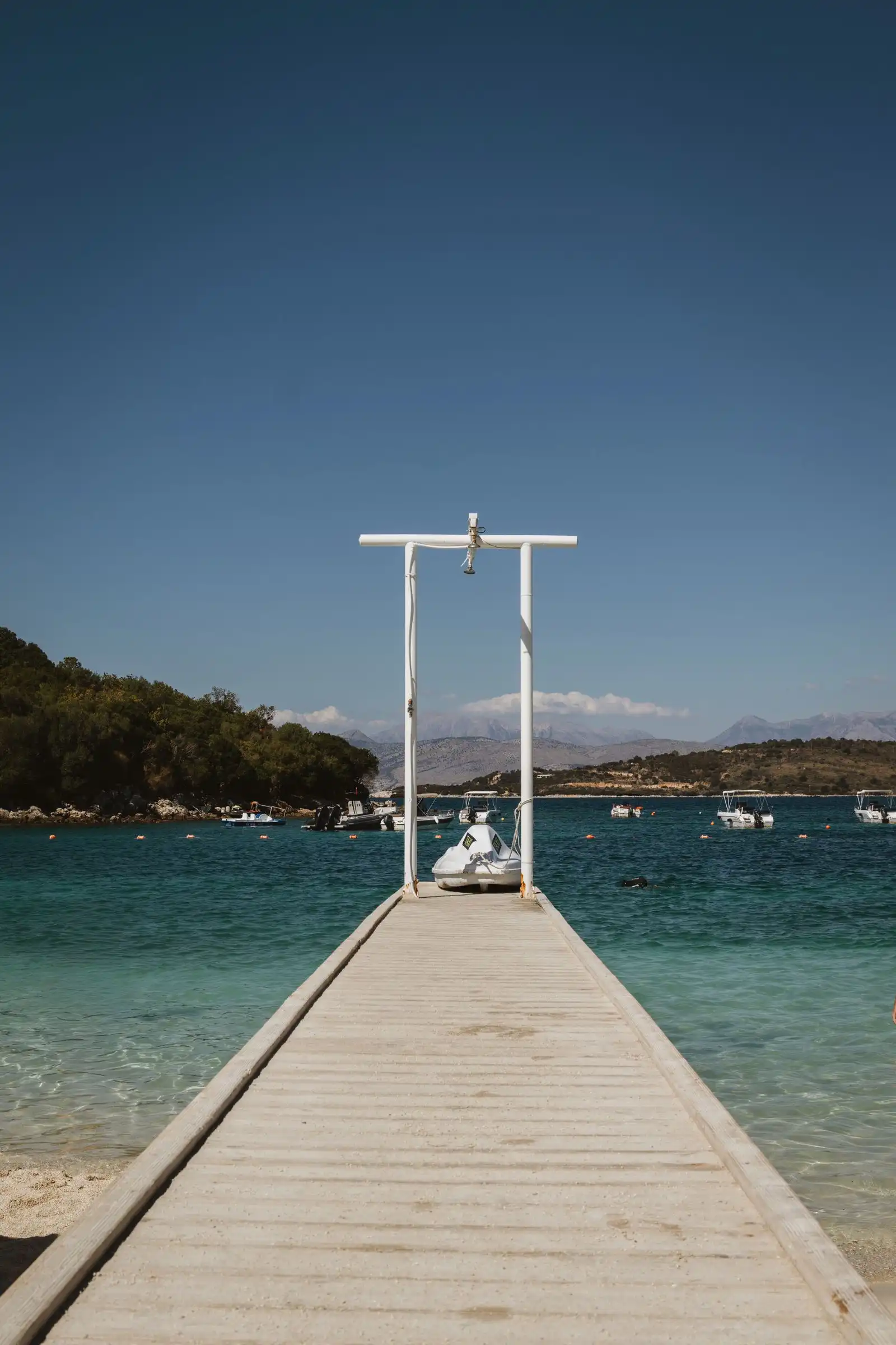 A wooden pier and small boats in a bay at Ksamil