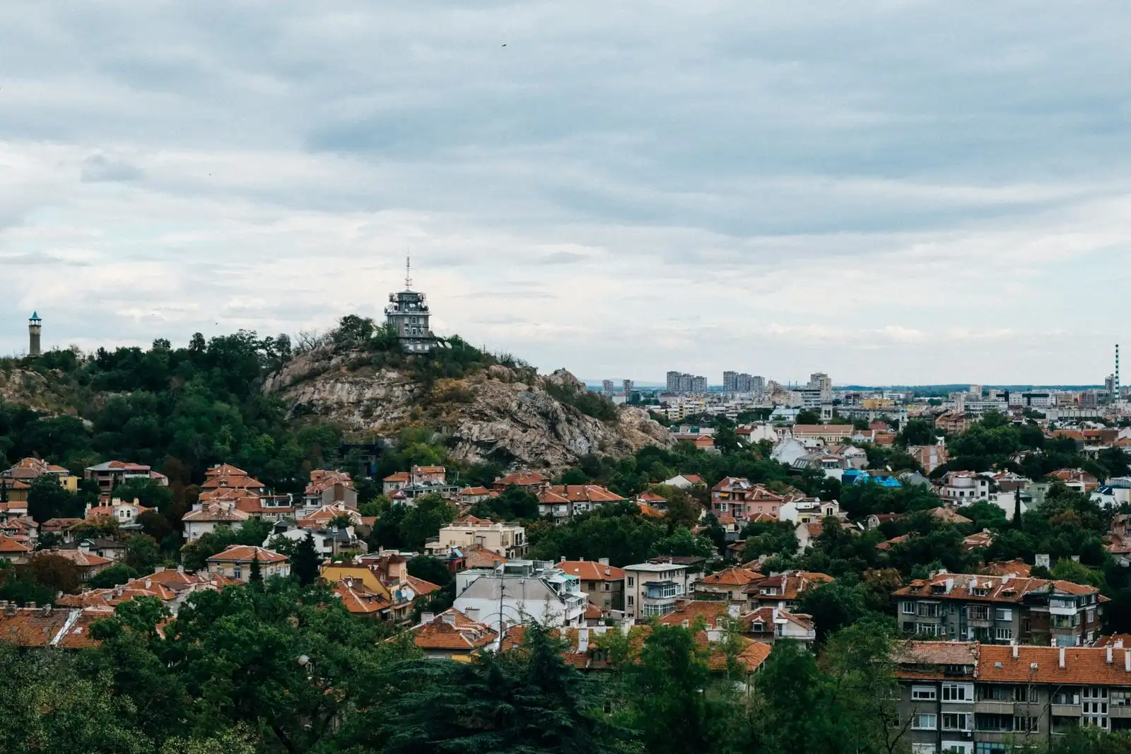 Plovdiv's rooftops spread below green hills