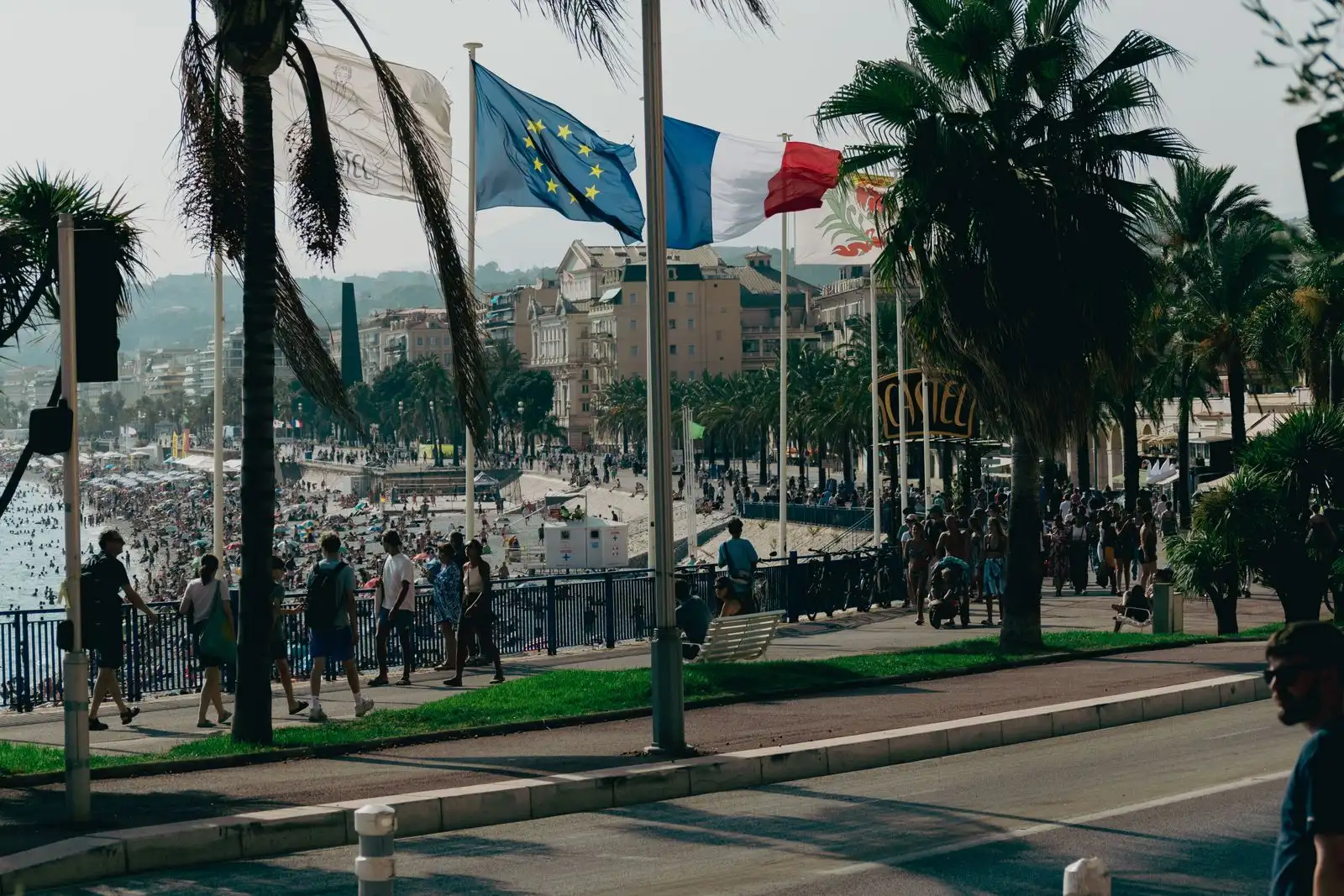 Palm trees, flags and visitors on Nice's seafront promenade