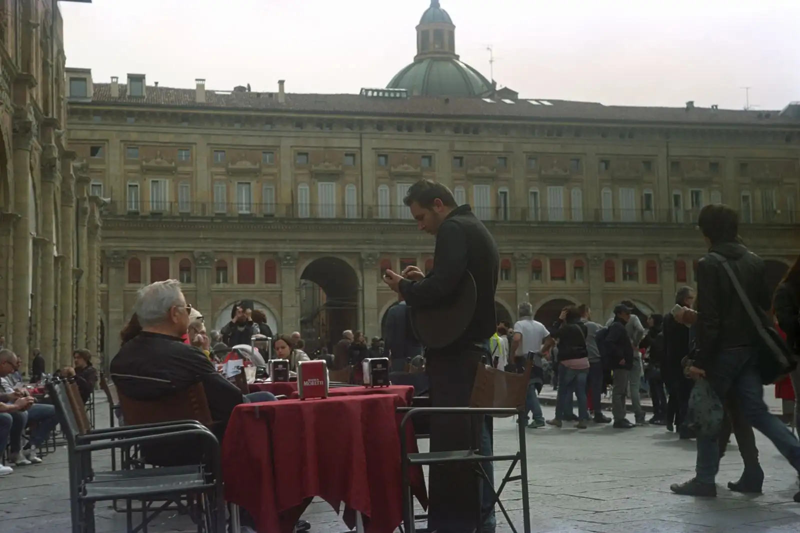 Visitors and cafe tables in Bologna's Piazza Maggiore
