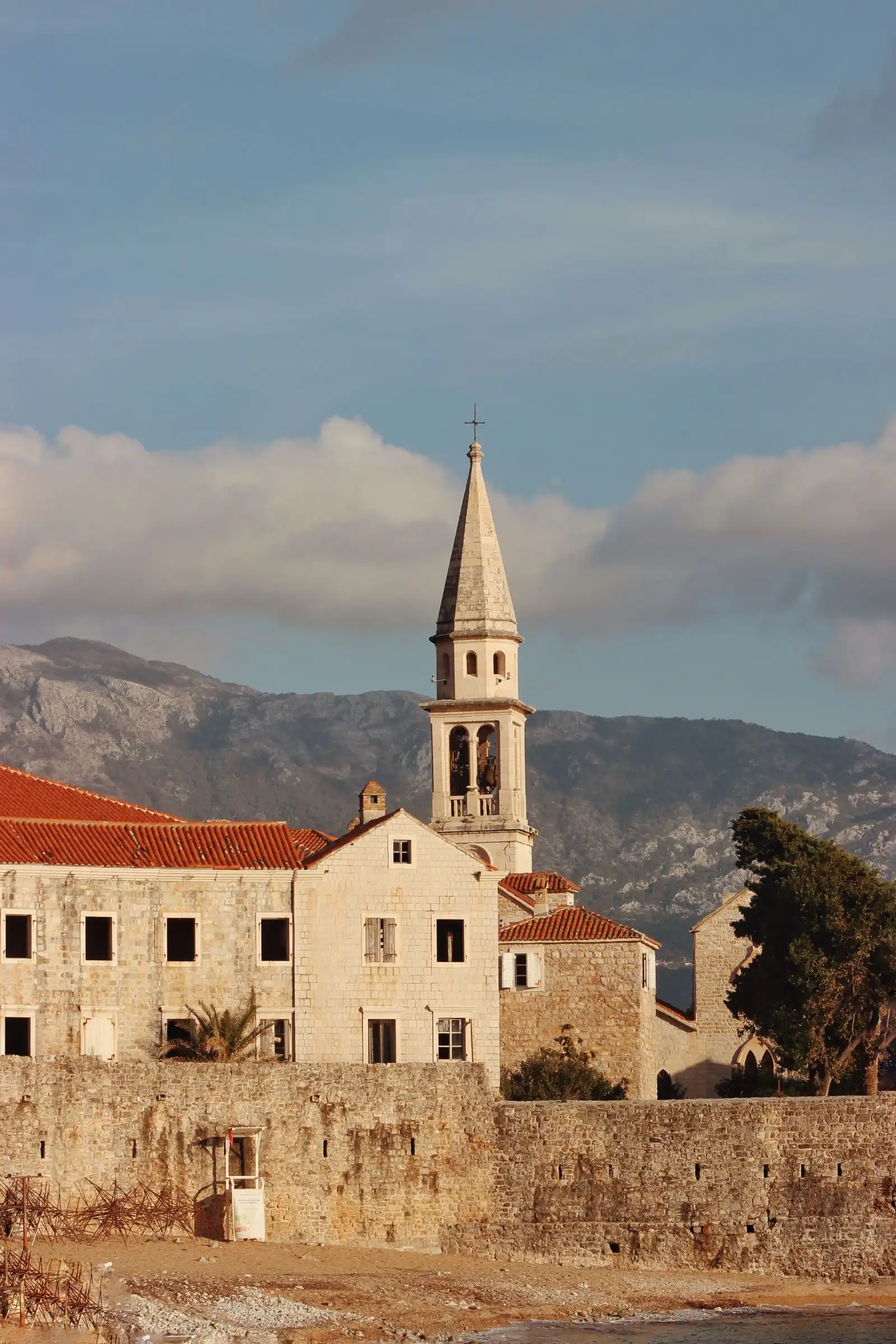 A church tower and red roofs in Budva's old town below the mountains
