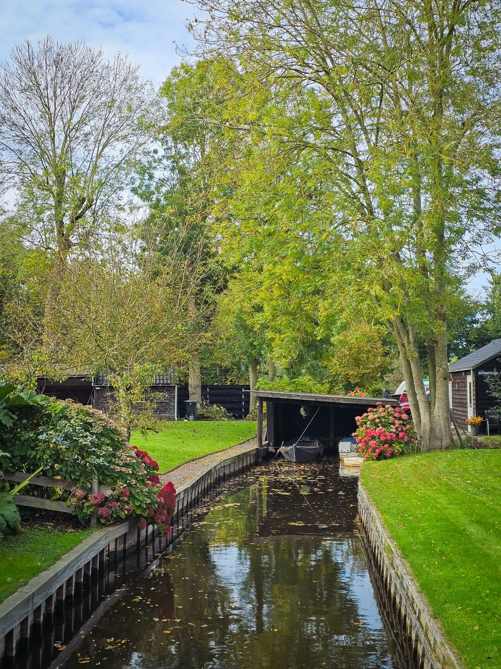 A canal between houses and green gardens in Giethoorn