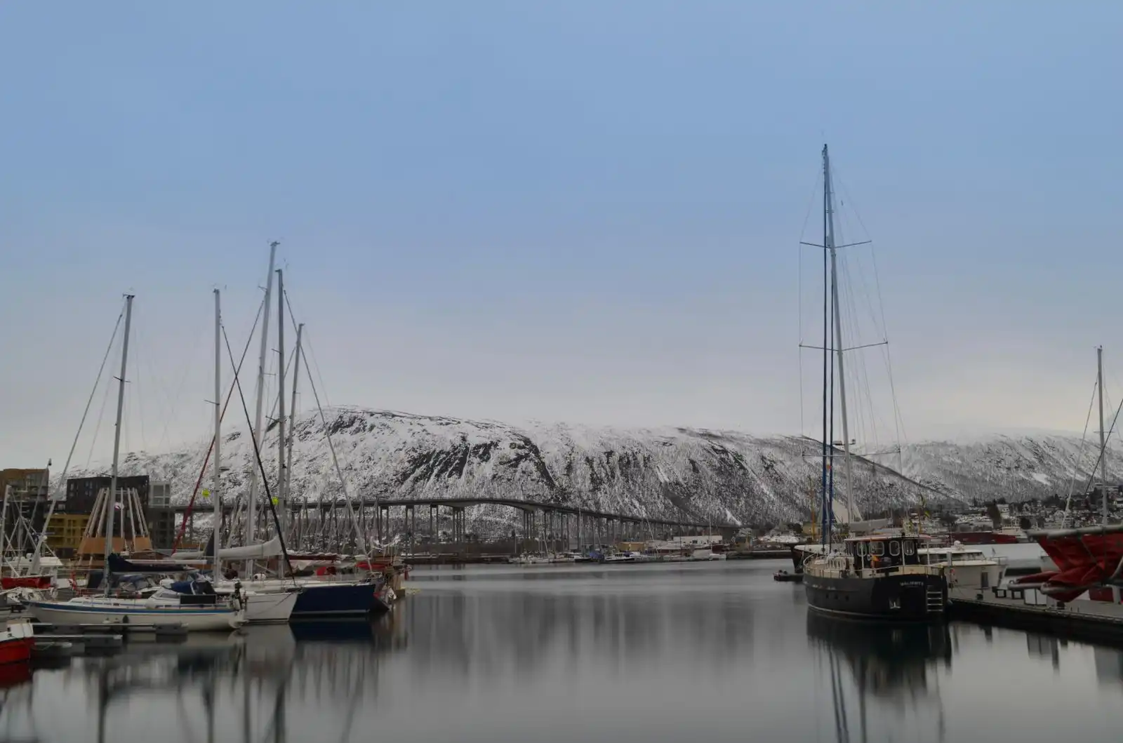 Boats in Tromsø's harbour with snowy mountains beyond