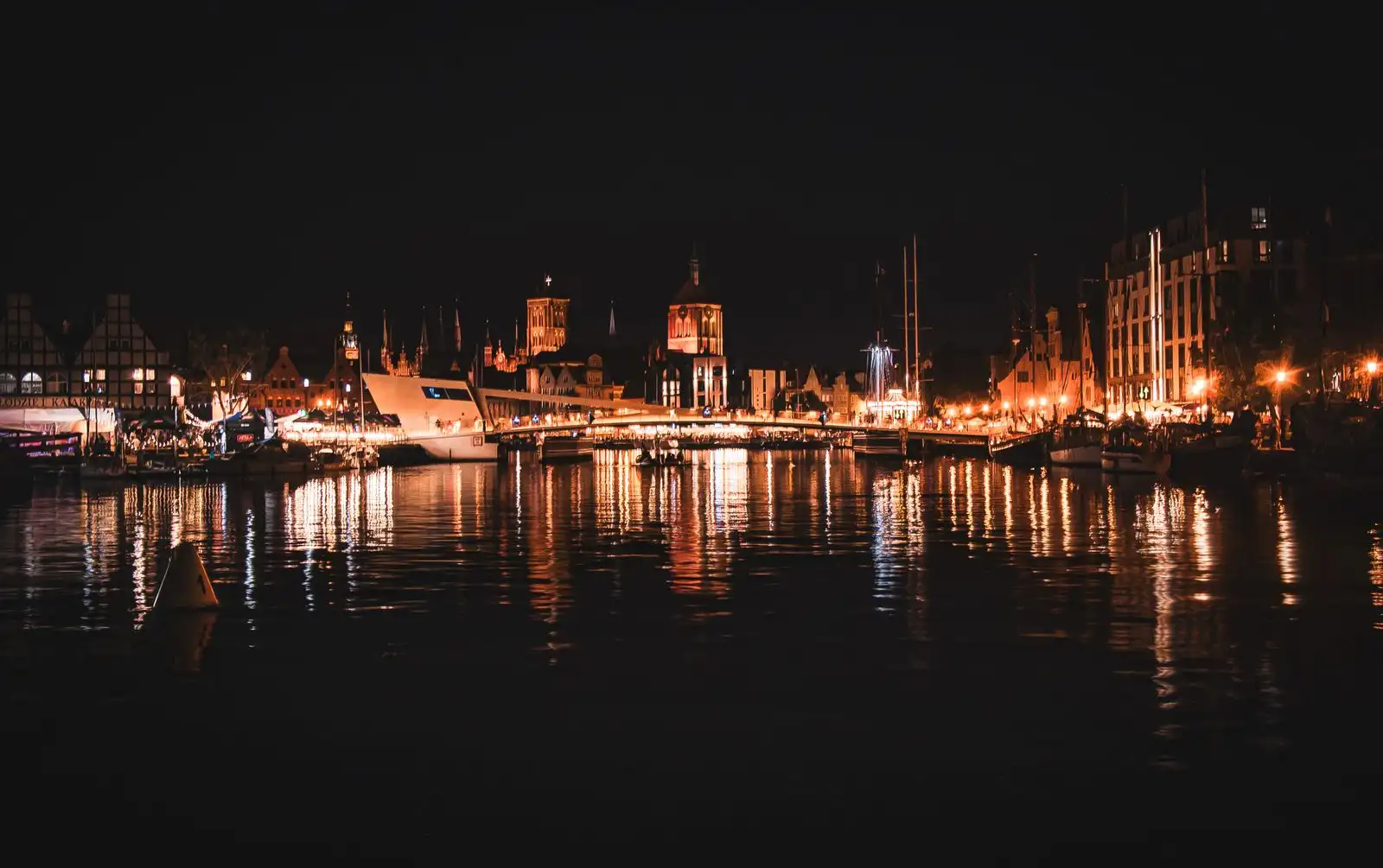 Gdańsk's old town buildings reflected in the river at night