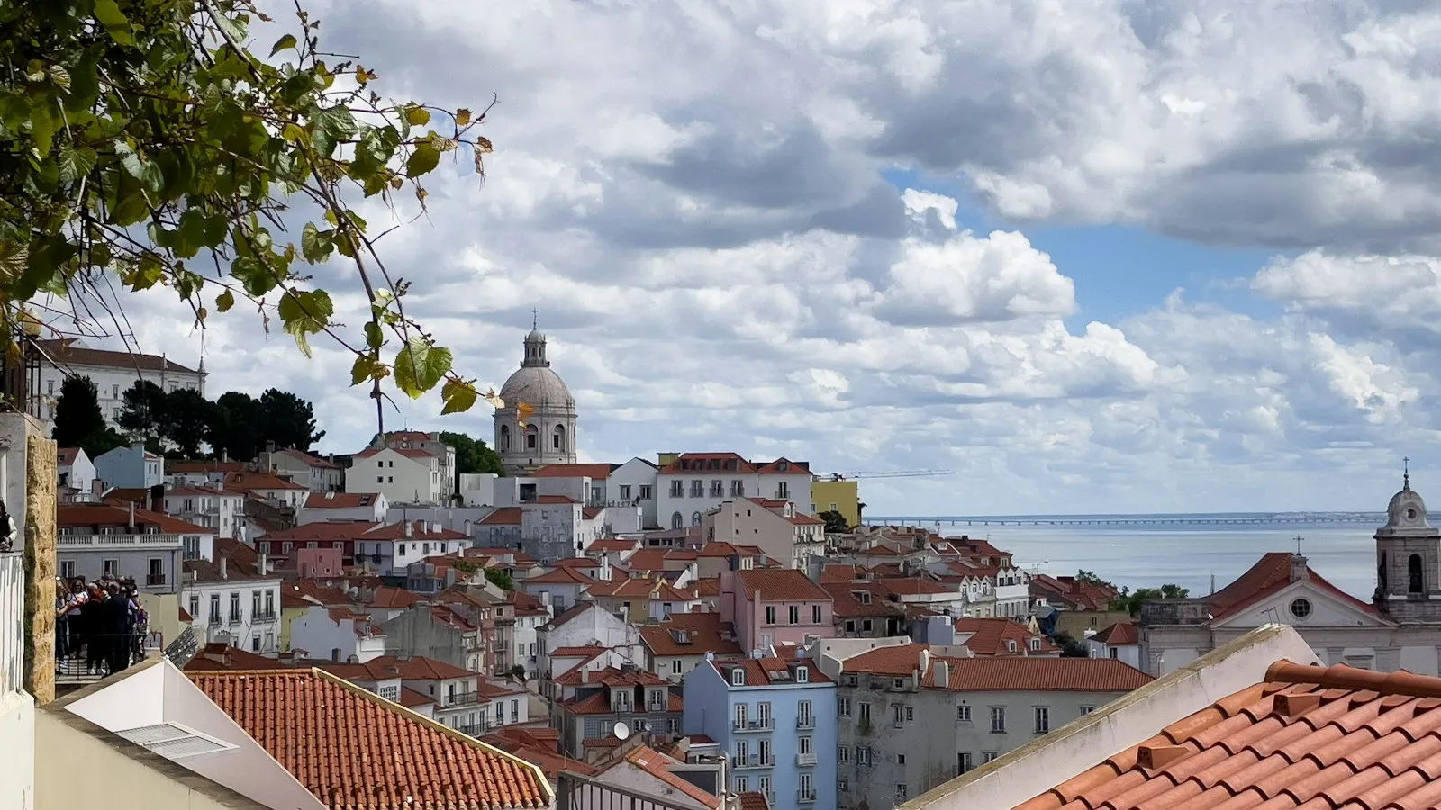 Red rooftops and a domed church above the Tagus River in Lisbon