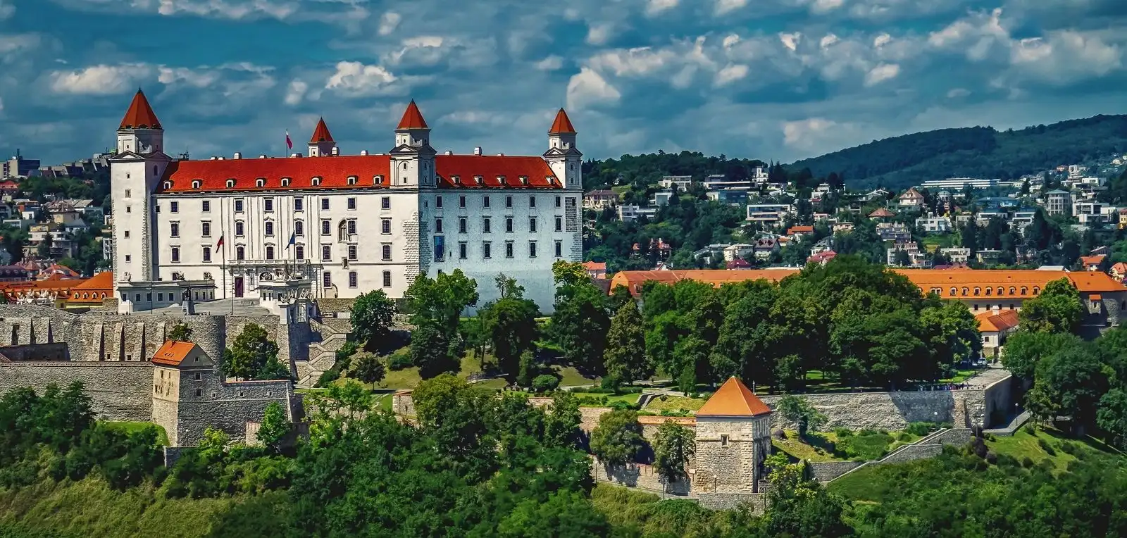 Bratislava Castle and the city's buildings above green hillsides