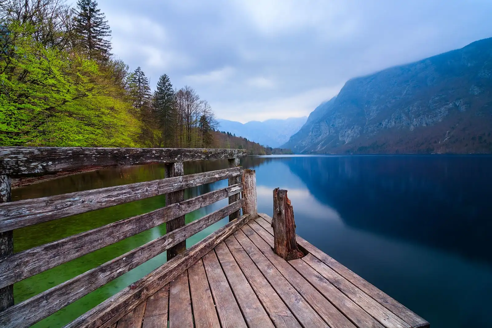 A wooden platform beside Lake Bohinj below forested mountains