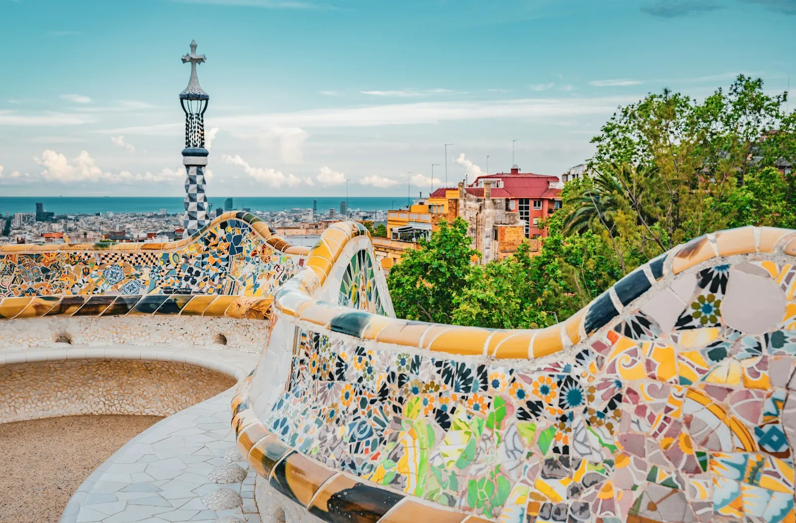 Curved mosaic benches and the tiled tower at Park Güell overlooking Barcelona