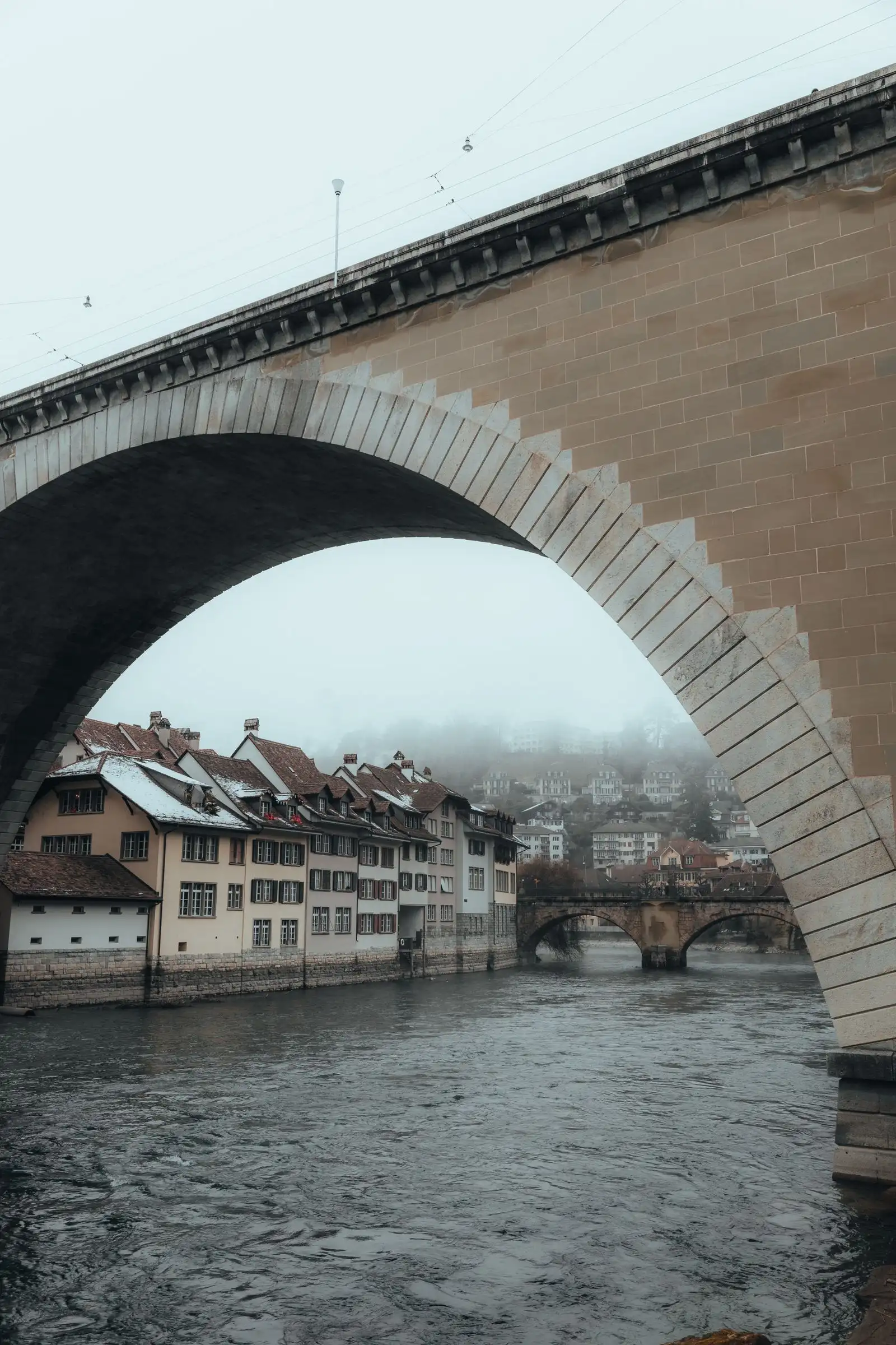 Bern's old town rooftops framed by a stone bridge arch