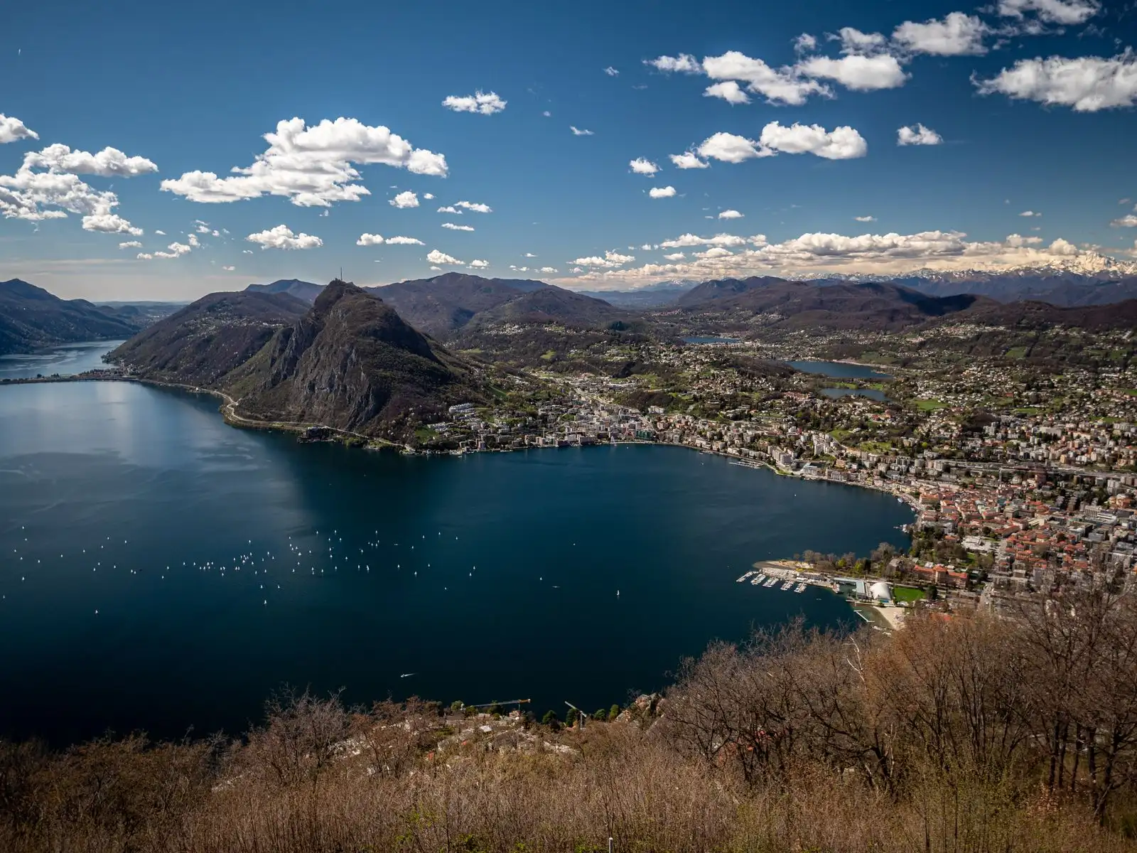 Lugano's buildings beside the lake below surrounding mountains