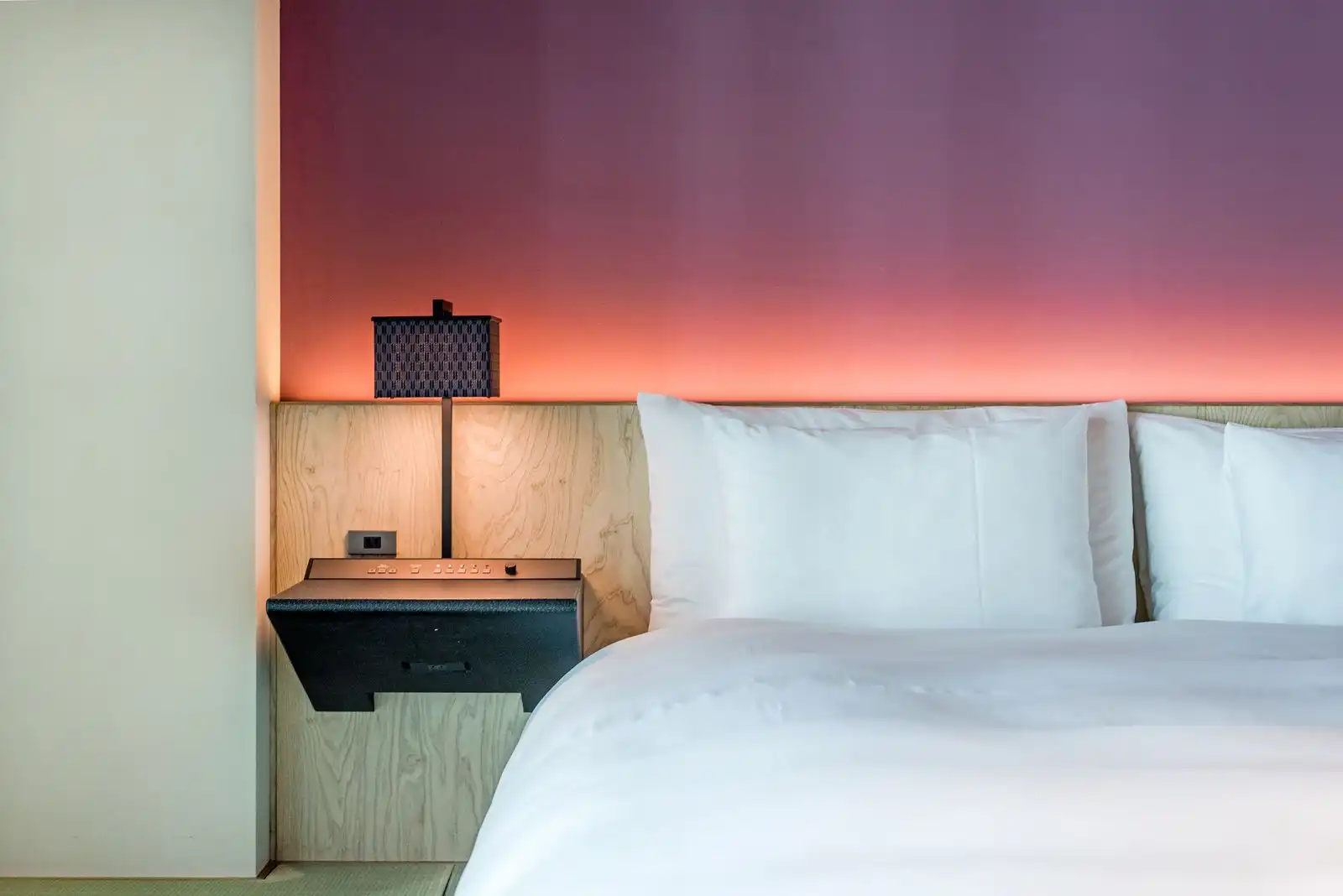 Double bed with white pillows and bedside lamps in a hotel room