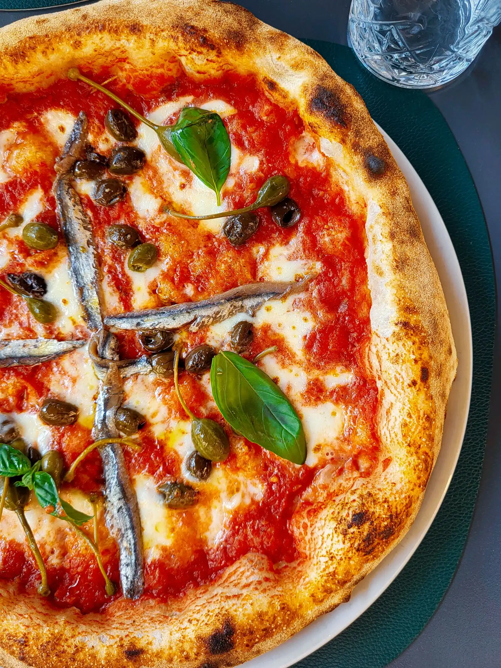 Pizza topped with anchovies, olives and basil