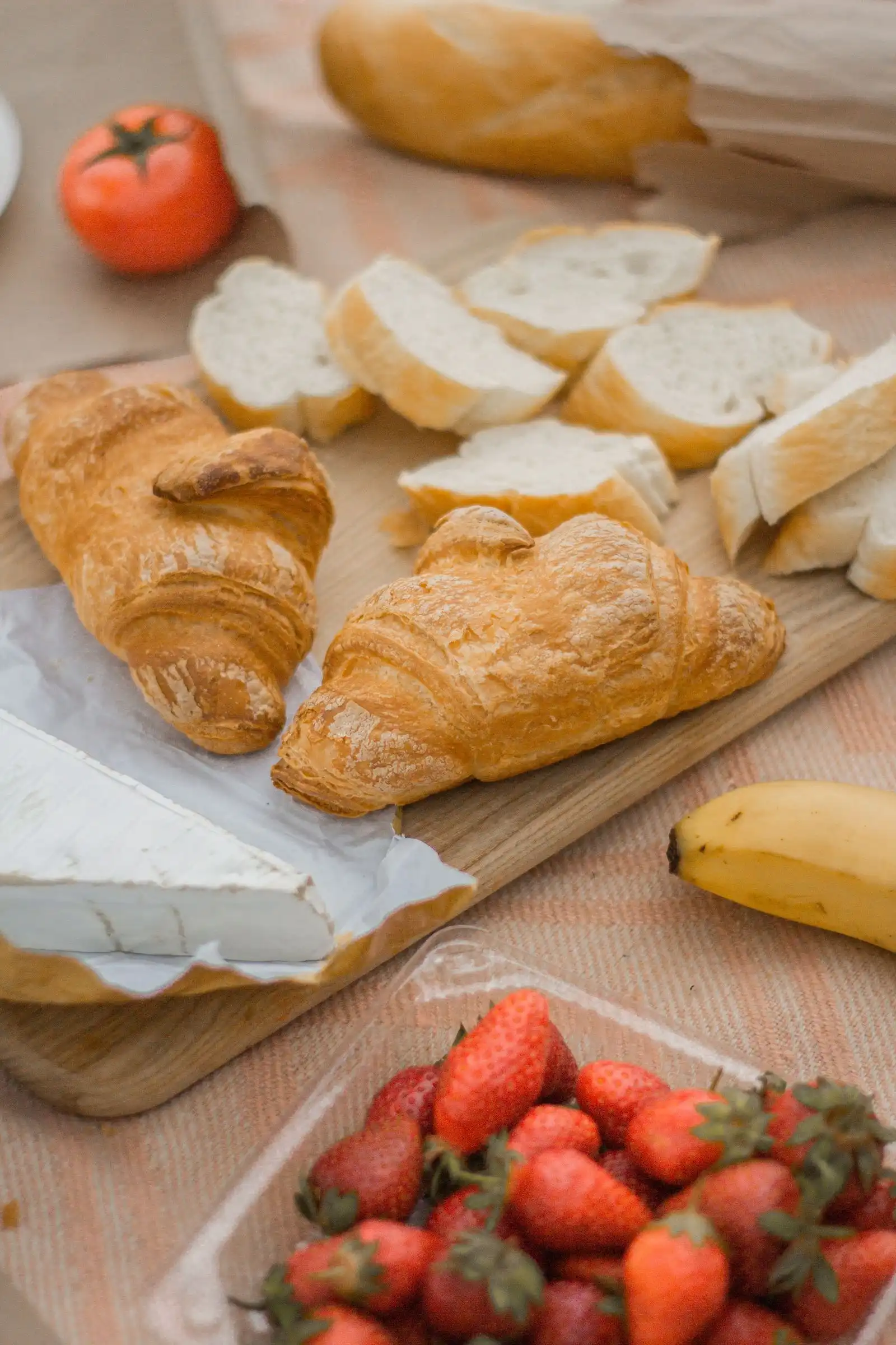 Bread, cheese, pastries and fruit arranged for a picnic