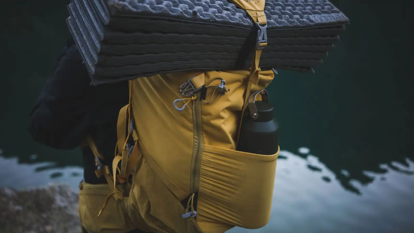 Yellow backpack carrying a water bottle and sleeping mat