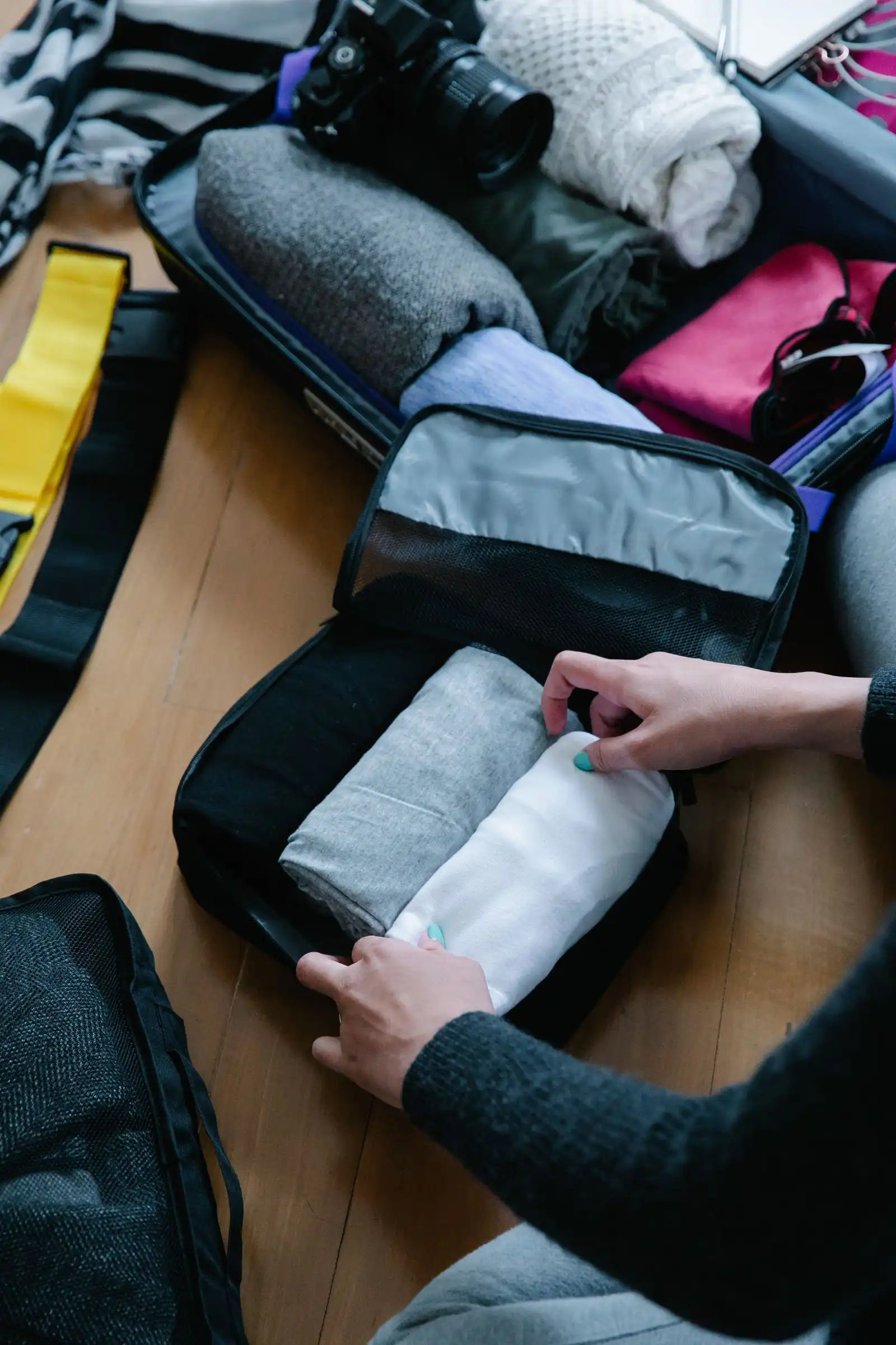 Hands rolling clothes into an open packing cube