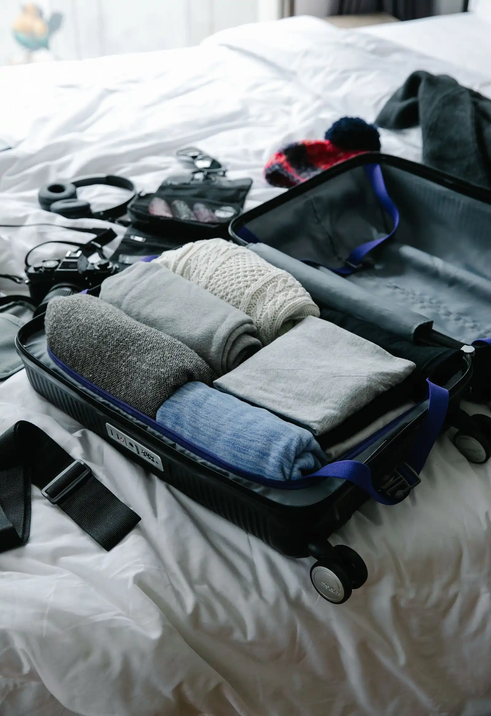 An open suitcase with folded clothes on a bed