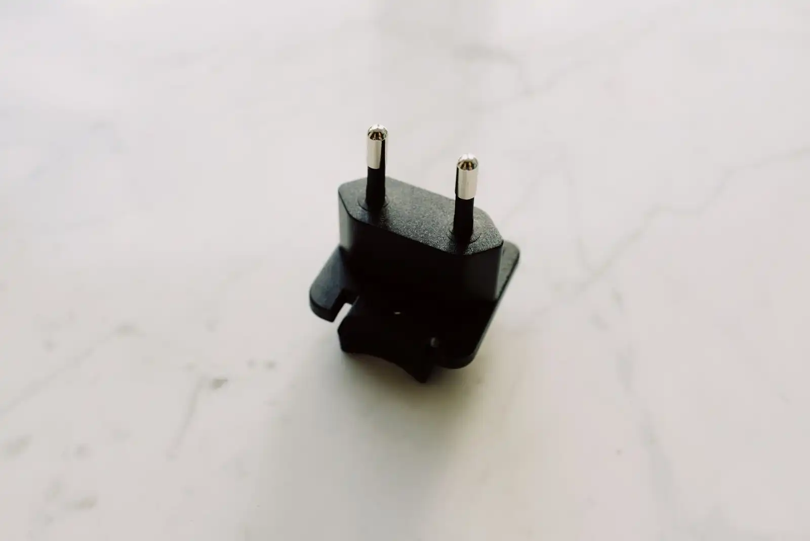 Black plug adapter with two round pins on a white surface
