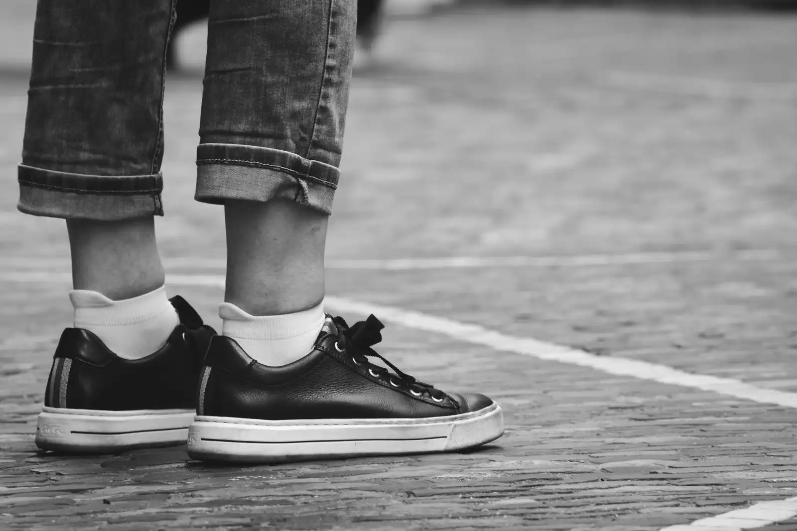 A person's trainers on cobblestone pavement