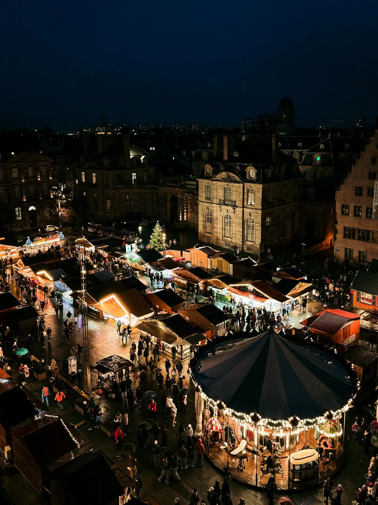 Illuminated Christmas market stalls and a carousel in Strasbourg