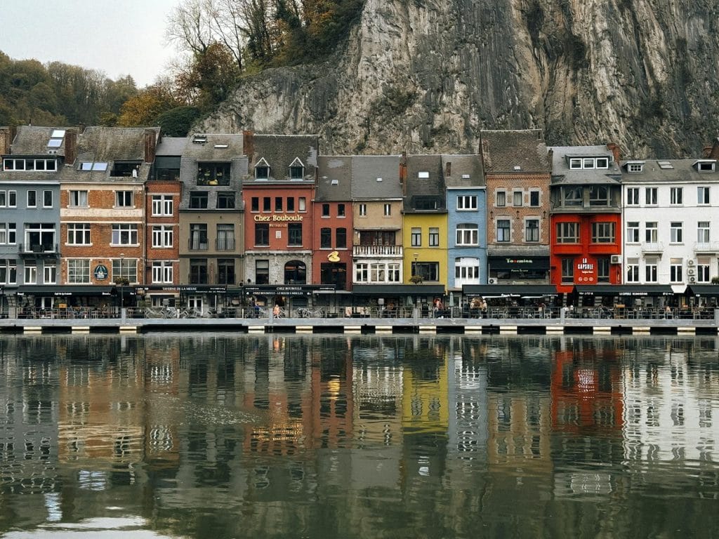 Charming colorful houses along the river in Dinant, Belgium, with reflections in water.