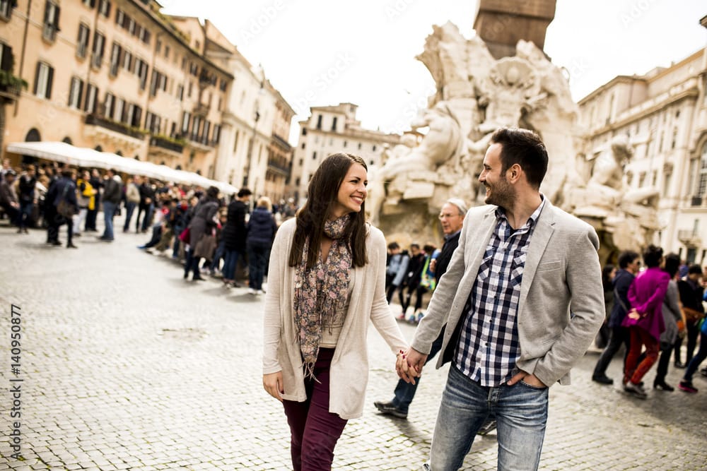 Casual young couple holding hands walking in Rome, Italy, Europe